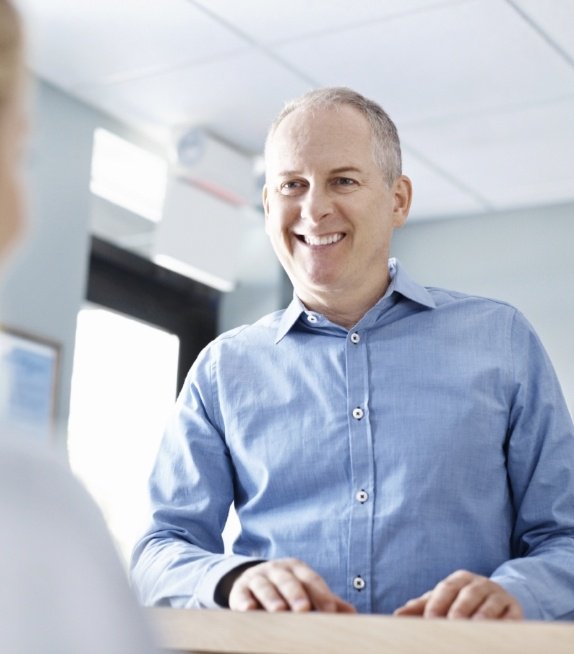 Man smiling at dental office receptionist