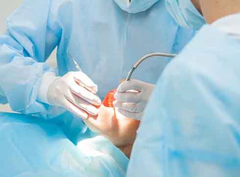  periodontists working in a patient’s mouth