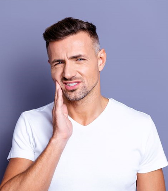 Wincing man holding his cheek