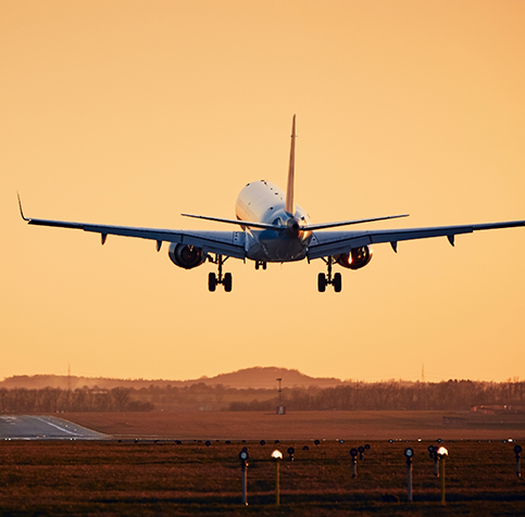 Image of plane landing during dusk with subtle mountain background