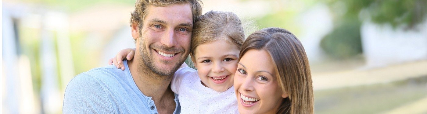 Family of three smiling outdoors after periodontal services in Corpus Christi