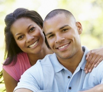 Man and woman smiling and hugging outdoors