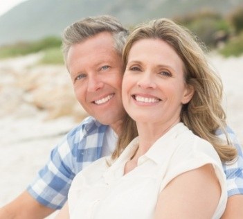Man and woman sitting on the beach and smiling