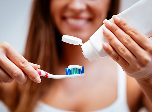woman putting toothpaste on toothbrush