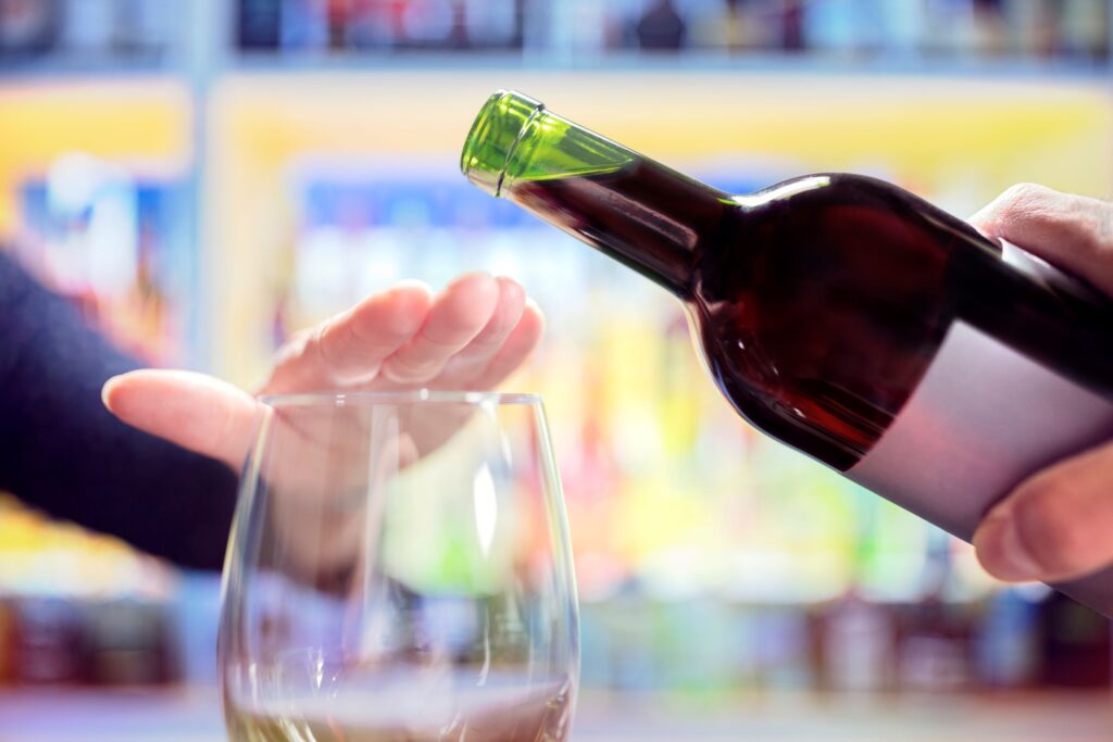 Hand covering empty glass so wine can't be poured in